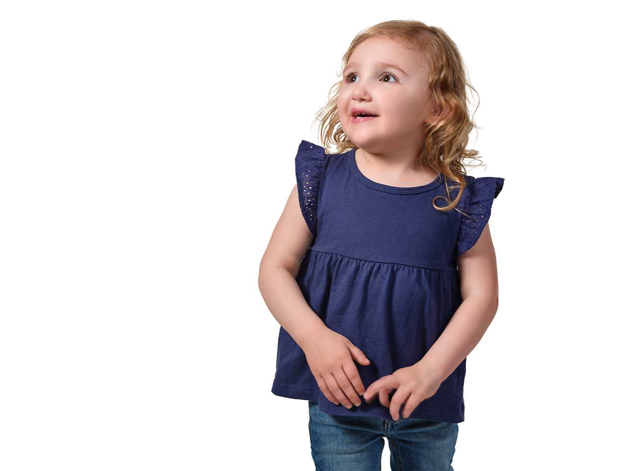 Young girl in dark blue shirt and jeans, arms and hands at her sides, looking up into the distance