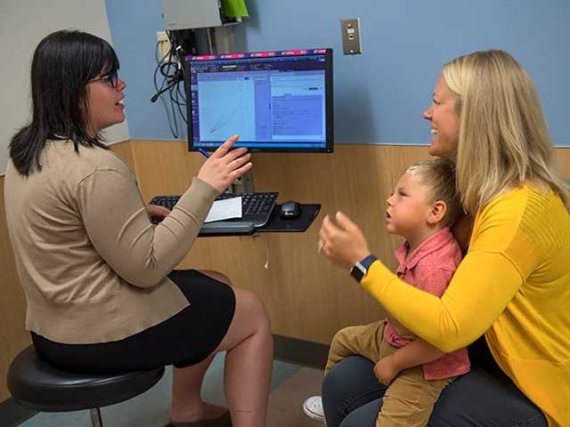 Mother holding son on lap while talking with Healthcare Provider.