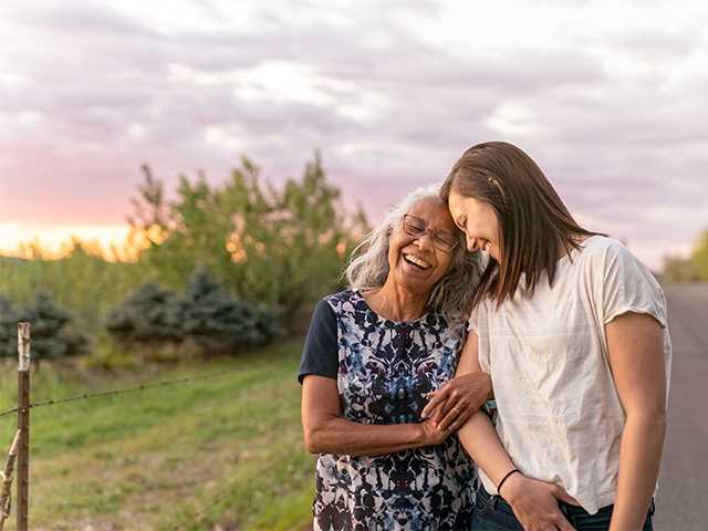 Woman hugging teen from the side.