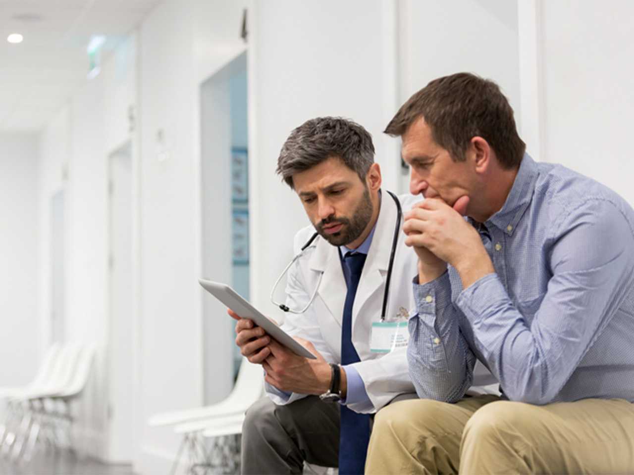 Healthcare provider showing man information on a tablet.