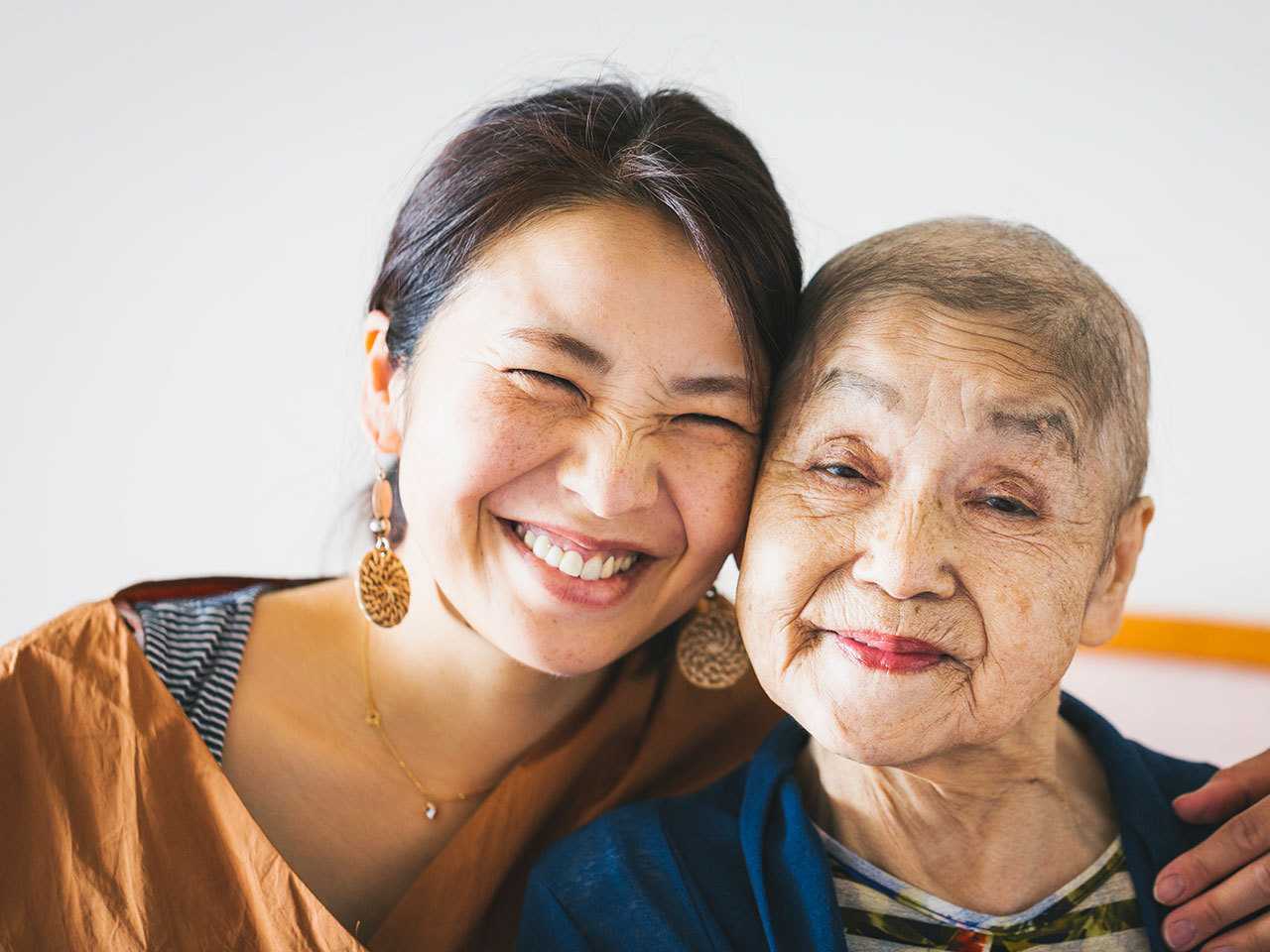 Smiling brown-haired young woman with her arm around a smiling short-haired elderly woman