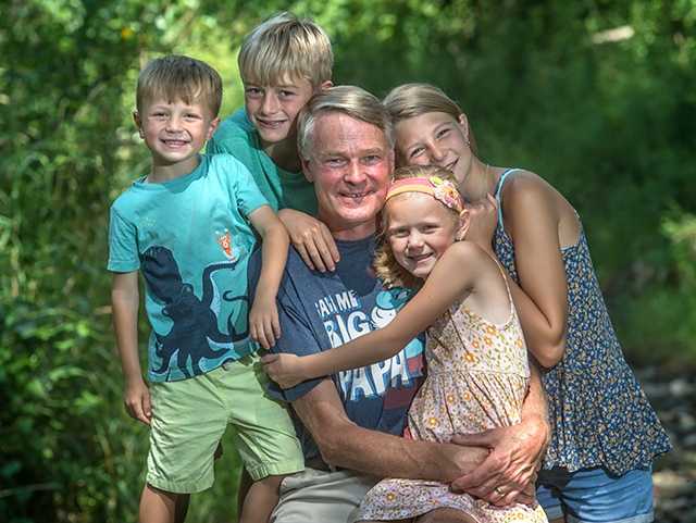 Man surrounded by young children around his neck.