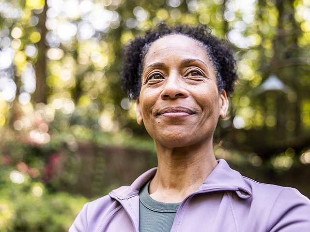 Dark haired middle aged woman standing outside smiling