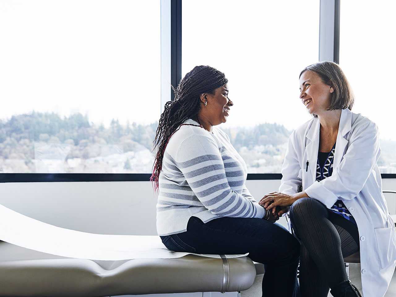 Female doctor in white lab coat sitting next to female patient